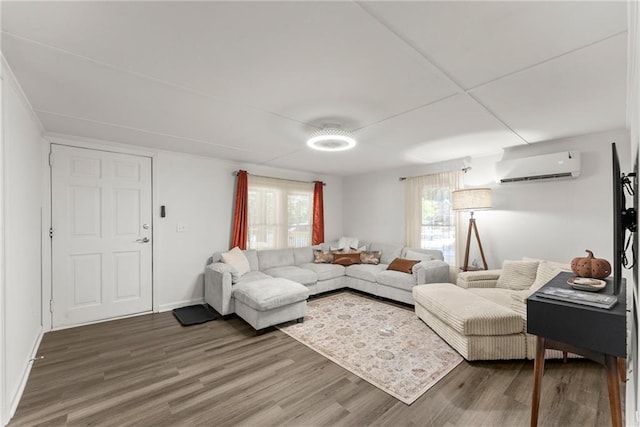 living area with a wall unit AC, baseboards, and wood finished floors