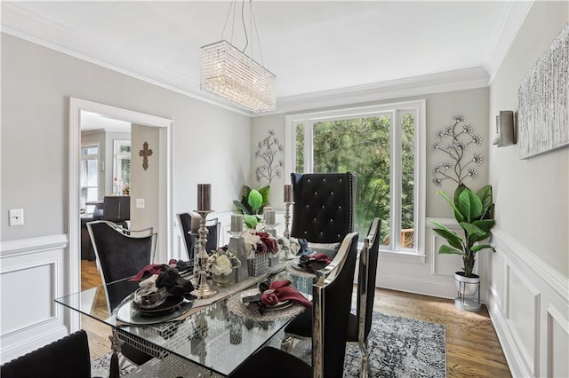 dining space featuring ornamental molding, hardwood / wood-style flooring, a healthy amount of sunlight, and a notable chandelier