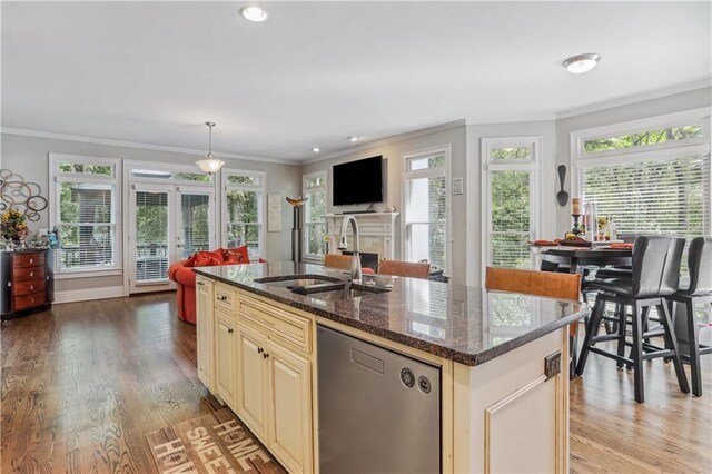 kitchen with sink, light hardwood / wood-style flooring, stainless steel dishwasher, dark stone countertops, and an island with sink