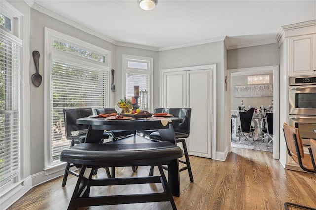 dining space with light wood-type flooring and ornamental molding