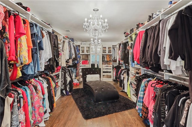 spacious closet with hardwood / wood-style flooring and a chandelier