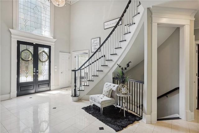 foyer featuring french doors, a towering ceiling, a chandelier, and light tile patterned floors