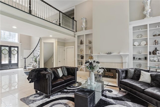 tiled living room featuring a high ceiling, french doors, and built in shelves