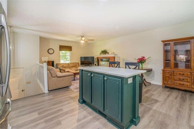 kitchen featuring a kitchen island, ceiling fan, stainless steel fridge, and light hardwood / wood-style floors