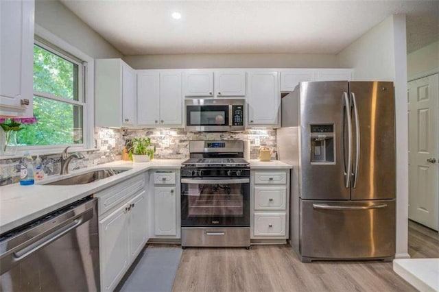 kitchen with white cabinets, appliances with stainless steel finishes, light hardwood / wood-style floors, sink, and tasteful backsplash