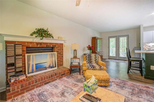 living room featuring ceiling fan, a fireplace, dark hardwood / wood-style floors, and french doors