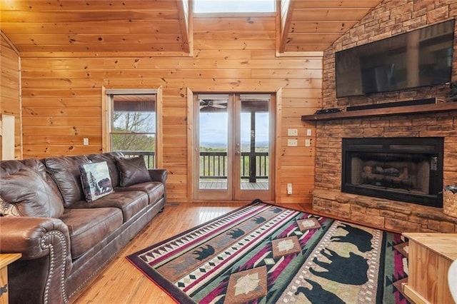 living room with lofted ceiling, wood walls, wood-type flooring, french doors, and a fireplace