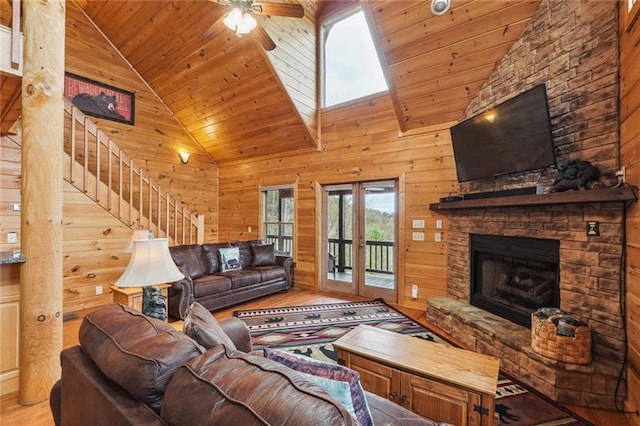 living room with high vaulted ceiling, wooden walls, and light hardwood / wood-style floors