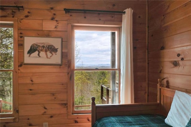 bedroom featuring wood walls and multiple windows