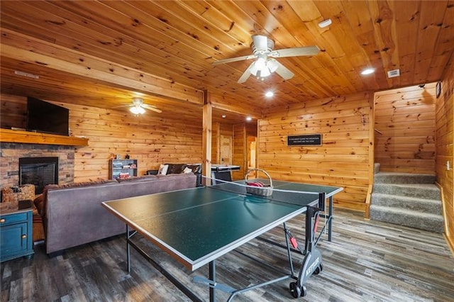 recreation room featuring wood ceiling, wood walls, a fireplace, and dark wood-type flooring