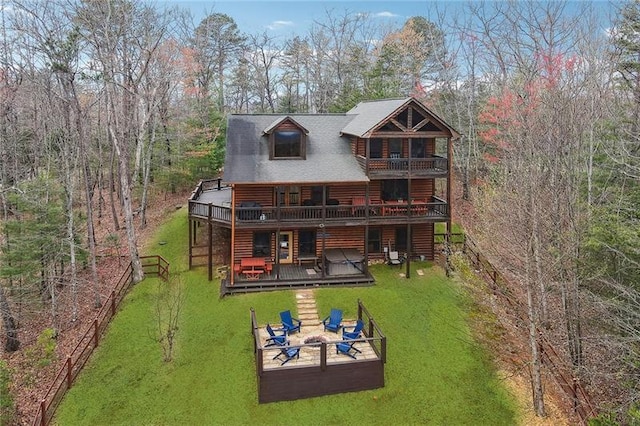 rear view of house with a lawn, an outdoor fire pit, and a deck