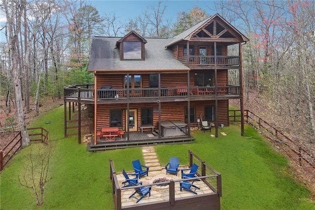 back of property featuring a wooden deck, a lawn, and a fire pit