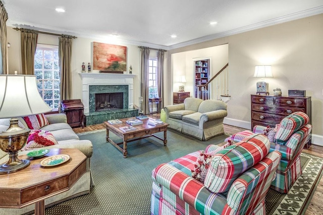 living room with a fireplace, wood finished floors, baseboards, stairway, and crown molding