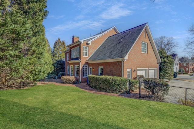 rear view of house with a garage, a yard, brick siding, and a chimney