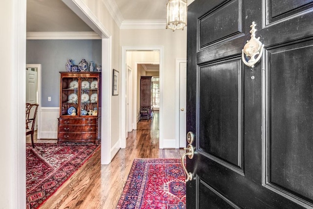 entrance foyer with a chandelier, crown molding, and wood finished floors