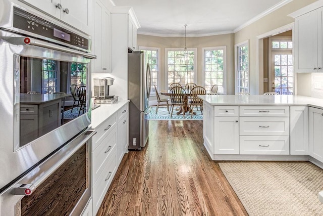 kitchen with light countertops, stainless steel appliances, crown molding, and wood finished floors