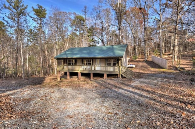 view of front of home with a forest view, metal roof, and a porch