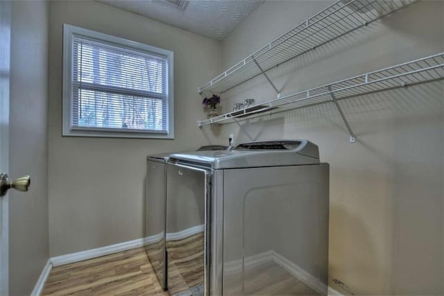 laundry room featuring baseboards, laundry area, wood finished floors, independent washer and dryer, and a textured ceiling