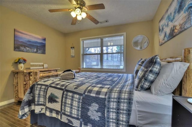 bedroom with visible vents, a ceiling fan, a textured ceiling, wood finished floors, and baseboards