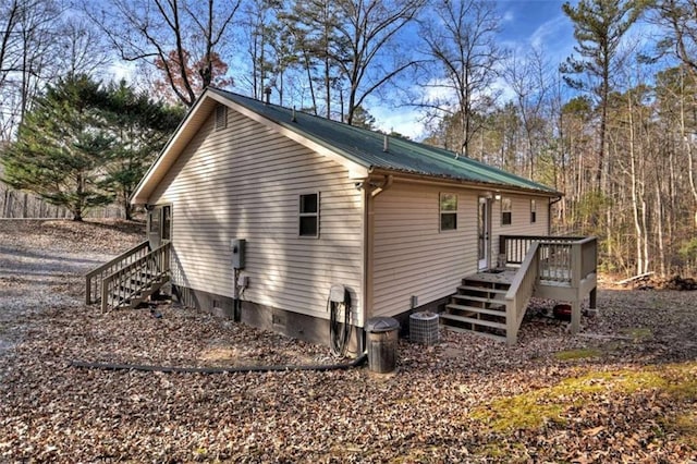 view of side of property featuring metal roof, central AC unit, and a wooden deck