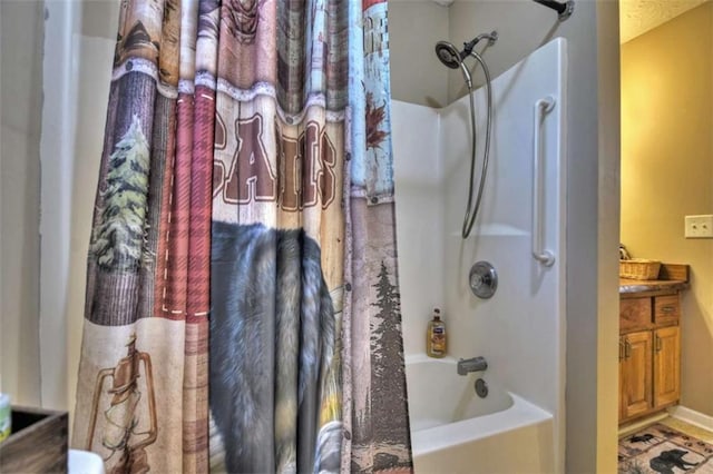 full bath with vanity, baseboards, and shower / bath combo