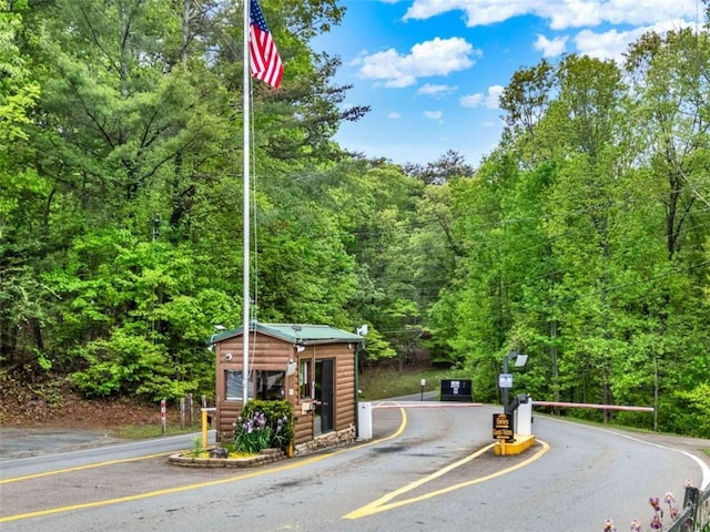 view of street with a gated entry and a wooded view