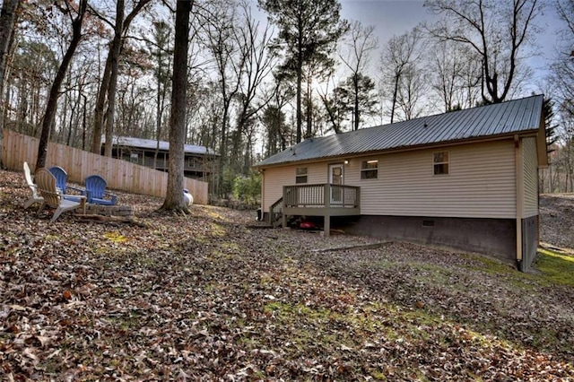 rear view of house with a wooden deck, crawl space, metal roof, and fence