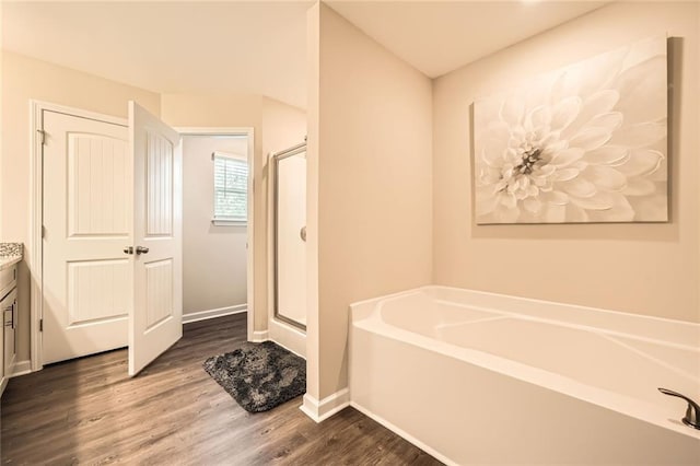 3070 Fareed St, Douglasville, GA 30135 - bathroom featuring vanity, wood finished floors, a bath, baseboards, and a shower stall