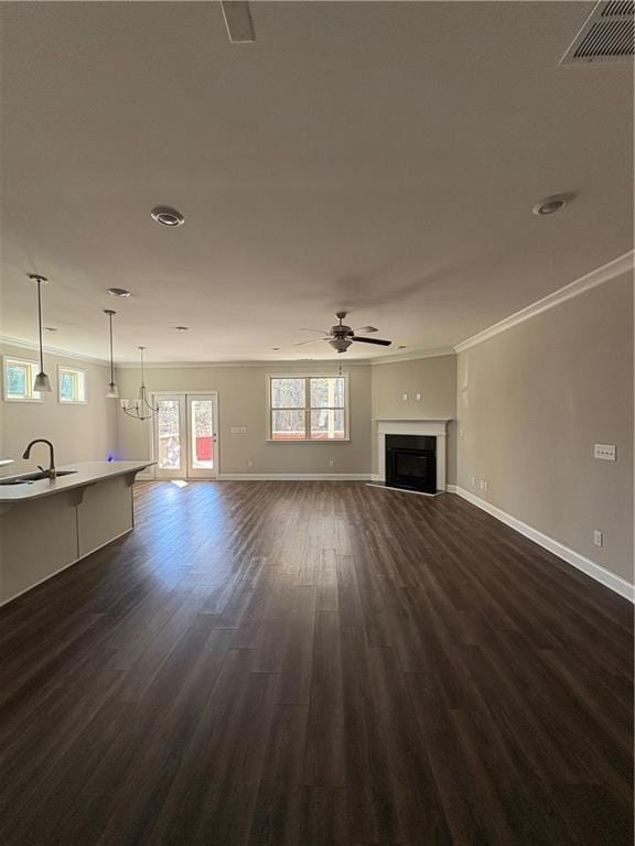 unfurnished living room featuring dark wood finished floors, a fireplace, visible vents, a sink, and baseboards