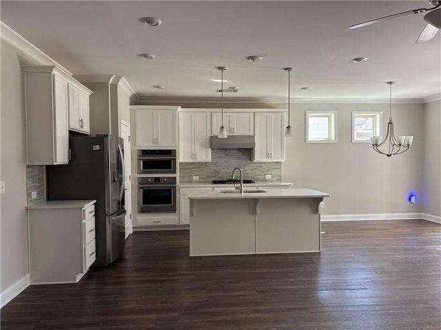 kitchen featuring dark wood finished floors, crown molding, stainless steel appliances, light countertops, and under cabinet range hood