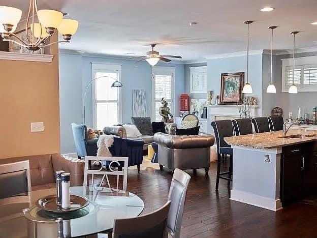 dining room featuring ceiling fan with notable chandelier, crown molding, dark wood-type flooring, and sink