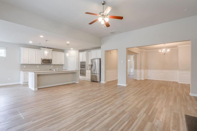 unfurnished living room featuring ceiling fan with notable chandelier and light hardwood / wood-style floors