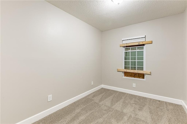 spare room featuring carpet floors, a textured ceiling, and baseboards