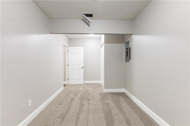 basement featuring carpet, a textured ceiling, and baseboards