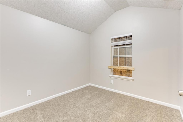 carpeted empty room featuring baseboards, vaulted ceiling, and a textured ceiling