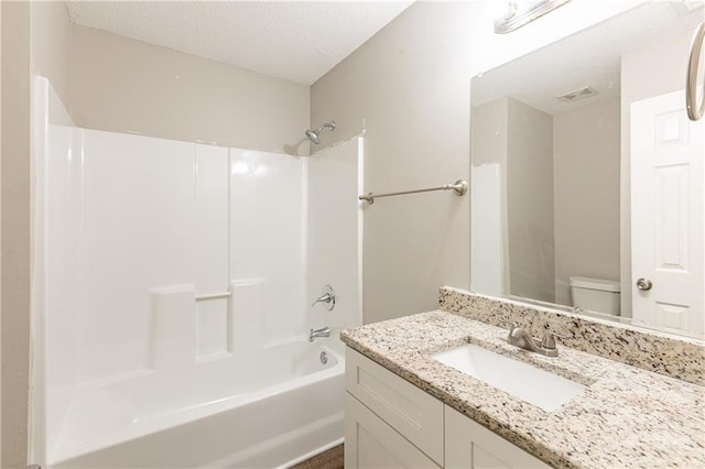 bathroom with a textured ceiling, washtub / shower combination, vanity, and toilet