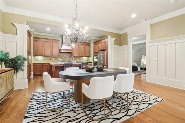 dining space featuring sink, crown molding, and light hardwood / wood-style flooring