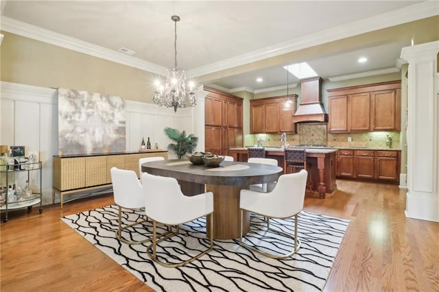 dining room with sink, crown molding, and light wood-type flooring