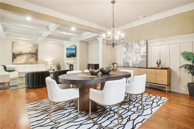 dining area featuring wood-type flooring, coffered ceiling, a notable chandelier, crown molding, and beam ceiling