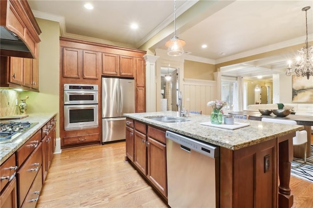 kitchen featuring hanging light fixtures, appliances with stainless steel finishes, a kitchen island with sink, and sink