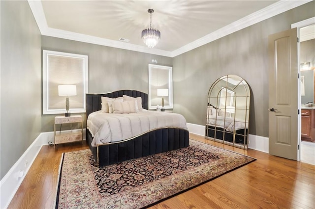 bedroom with crown molding, an inviting chandelier, and light hardwood / wood-style floors