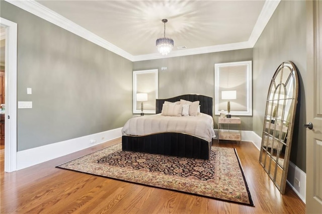 bedroom with hardwood / wood-style flooring, crown molding, and an inviting chandelier