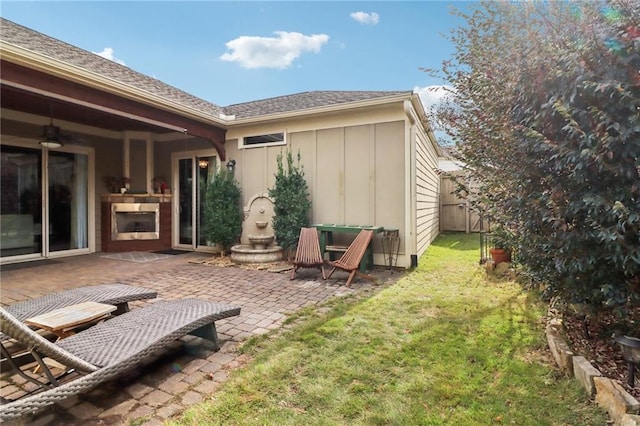 back of property featuring ceiling fan, a yard, a patio area, and an outdoor fireplace