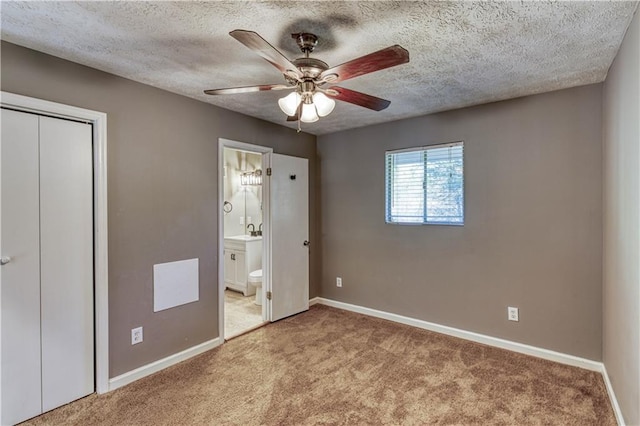 unfurnished bedroom featuring ensuite bath, ceiling fan, sink, light colored carpet, and a textured ceiling