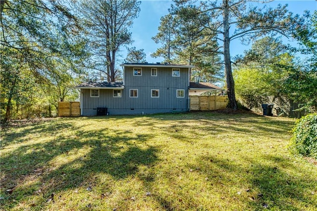 rear view of property with cooling unit and a yard