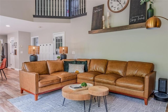 living area with recessed lighting, a high ceiling, baseboards, and wood finished floors