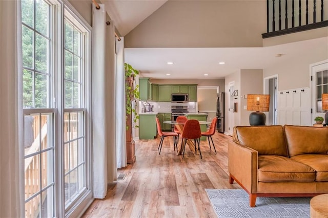 living room featuring recessed lighting, light wood finished floors, high vaulted ceiling, and visible vents