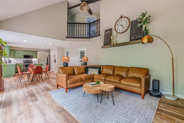 living room with high vaulted ceiling, recessed lighting, a ceiling fan, baseboards, and light wood-style floors