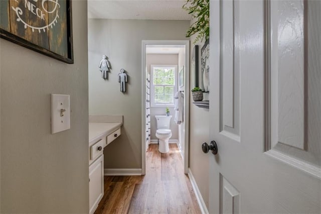 bathroom featuring vanity, toilet, baseboards, and wood finished floors