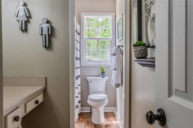 bathroom featuring toilet, wood finished floors, and baseboards